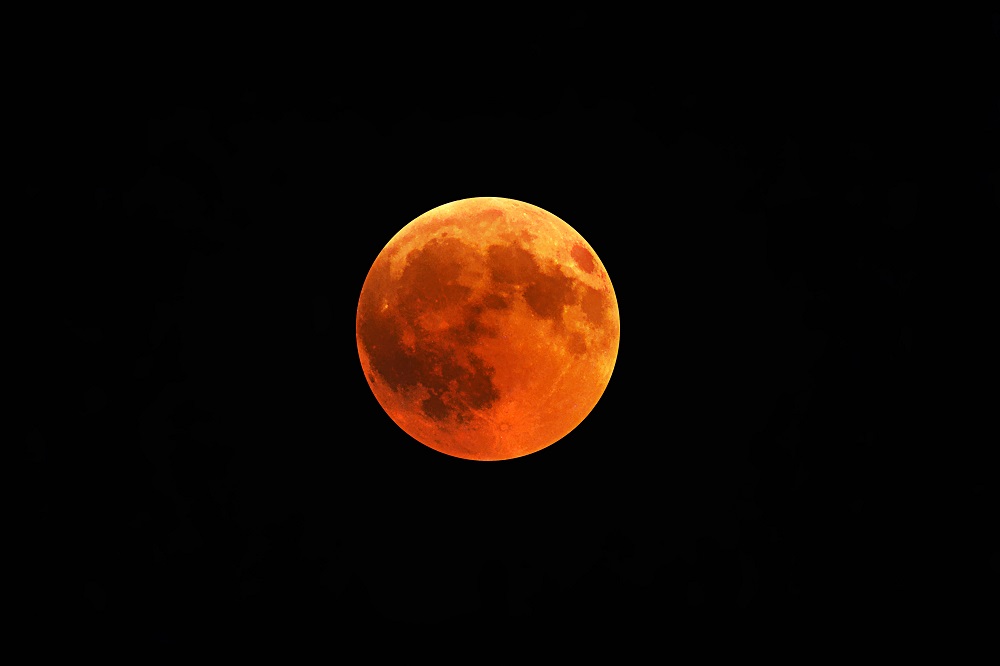 A beautiful shot of a red moon, total lunar eclipse with a black night sky in the background